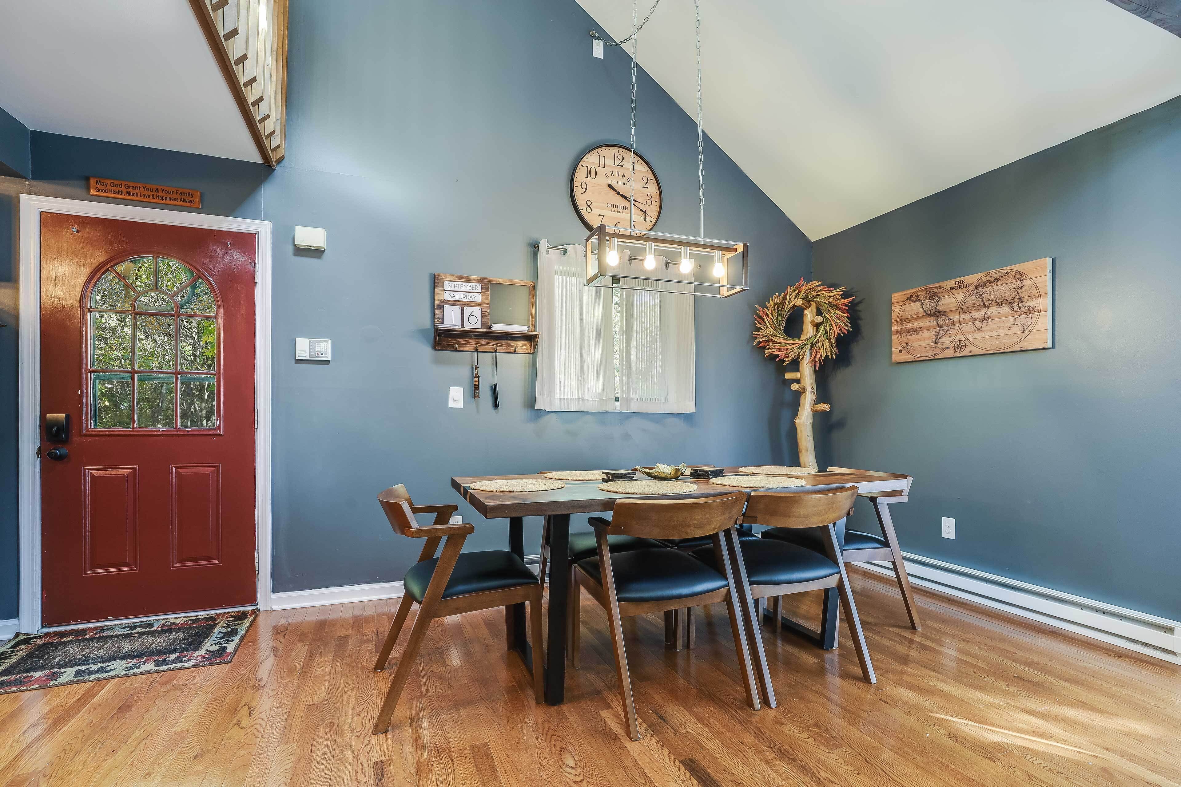 A dining area with a wooden table and chairs, a clock, and a world map on the wall.
