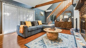 A modern living room with a grey sectional sofa, a wooden coffee table, and a patterned rug. - Hot Tub, Fire Pit & Barrel Sauna: Poconos Abode (Long Pond)
