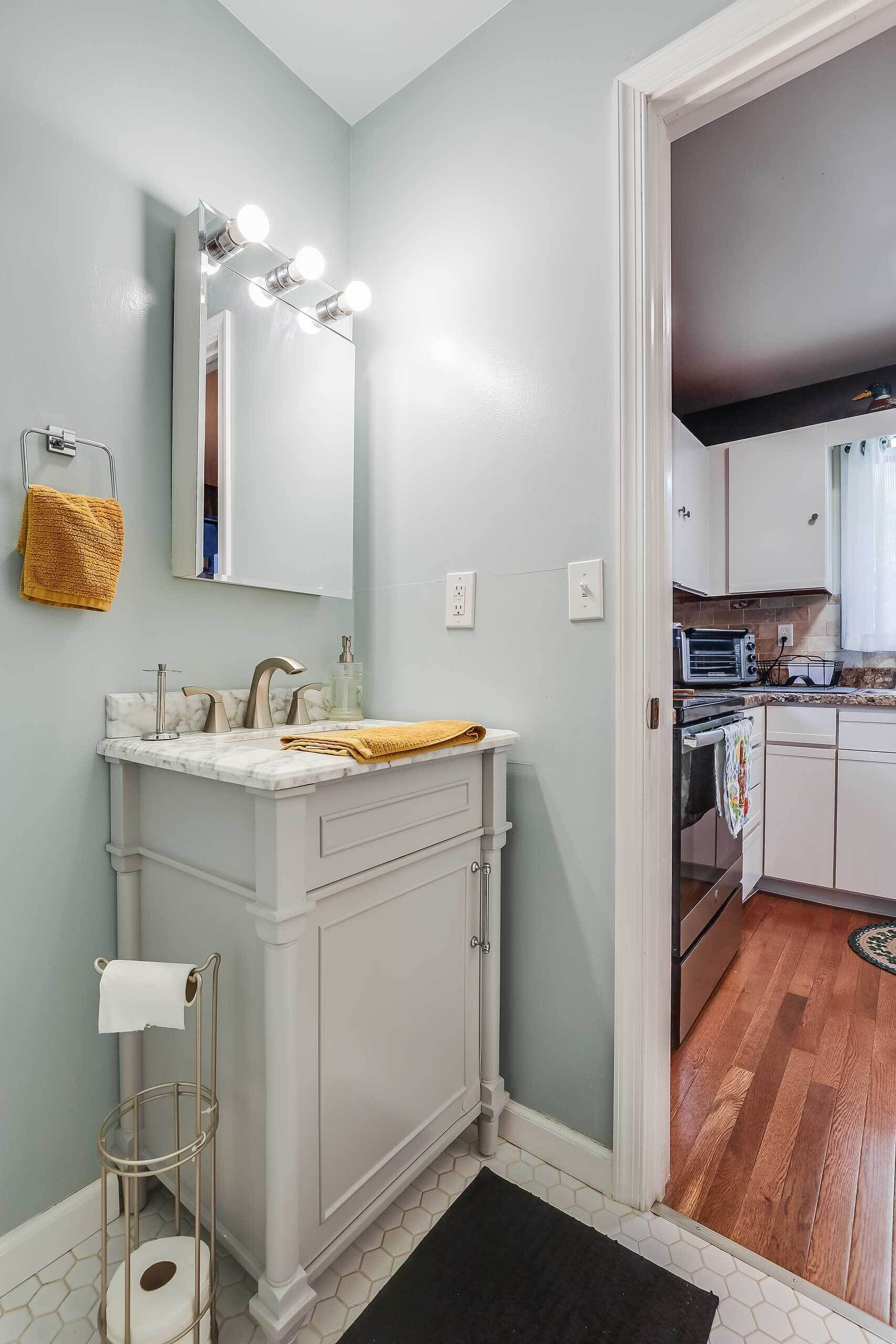 A modern bathroom with a vanity, mirror, and lighting.