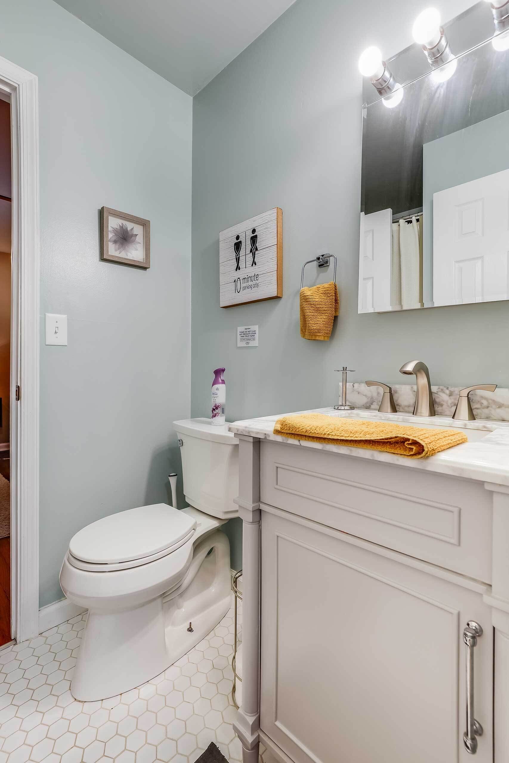 Une salle de bain avec des toilettes blanches, un lavabo avec un miroir et un porte-serviettes.