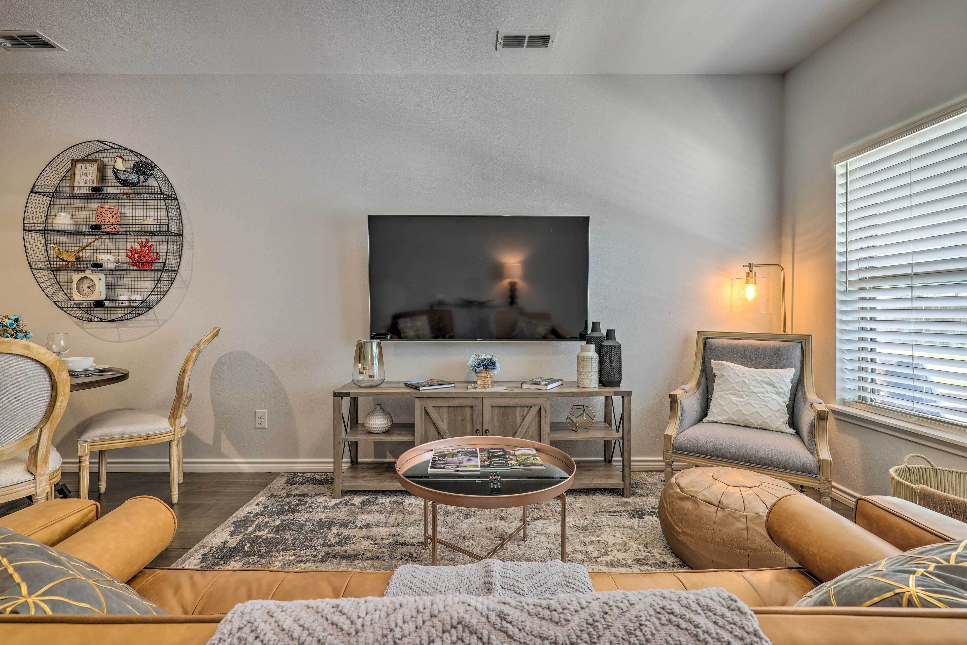 A living room with a sofa, armchairs, a coffee table, a TV, and a decorative wall shelf.