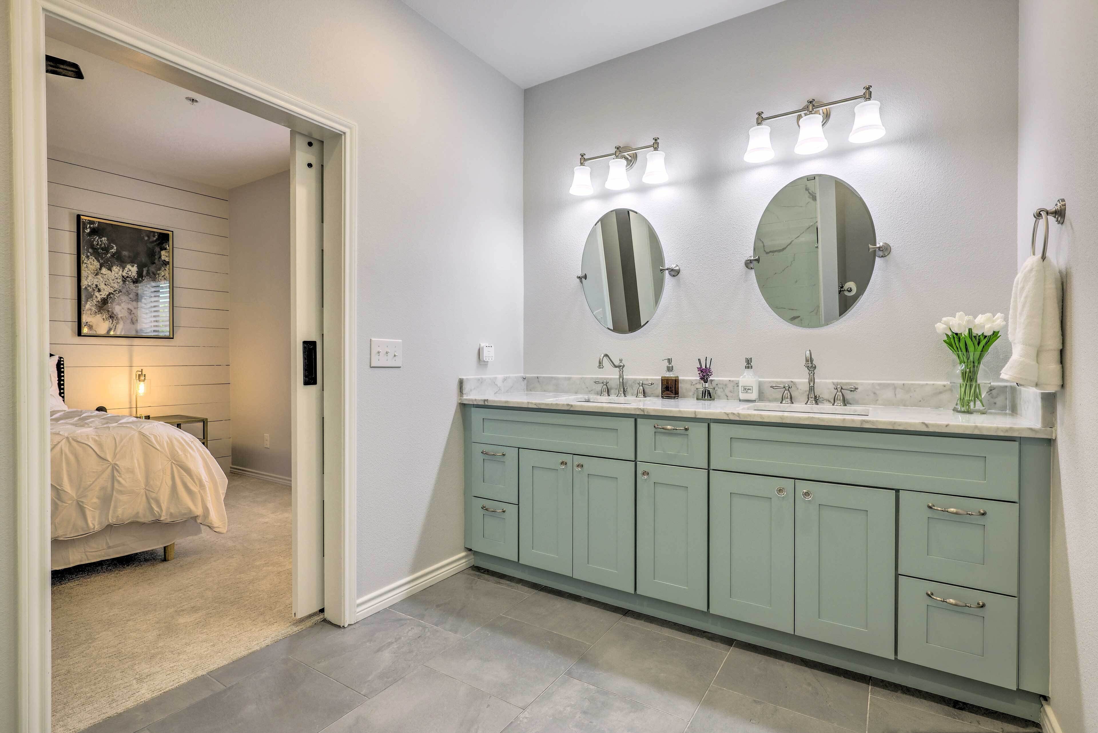 A bathroom with a double sink, two mirrors, and a towel rack.