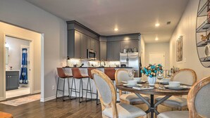 A modern kitchen with dark cabinets, stainless steel appliances, and a dining area with wooden chairs and a round table.