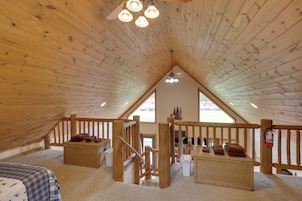 A cozy attic bedroom with wooden beams, a sloped ceiling, and a view of the outdoors.