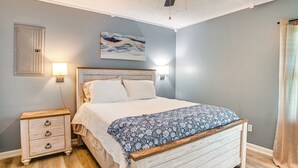 Une chambre à coucher avec un lit en bois, des tables de chevet, une lampe fixée au mur et un tableau.