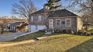 A two-story house with a front garage, a covered porch, and a well-maintained lawn. - Cozy Kansas City Home w/ Yard - 9 Mi to Dtwn! (Kansas City)