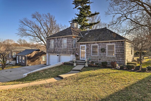 Une maison à deux étages avec un garage à l’avant, une véranda et une pelouse bien entretenue.