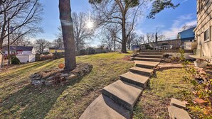 A residential property with a stone staircase leading to a front door, surrounded by a grassy lawn and trees. - Cozy Kansas City Home w/ Yard - 9 Mi to Dtwn! (Kansas City)
