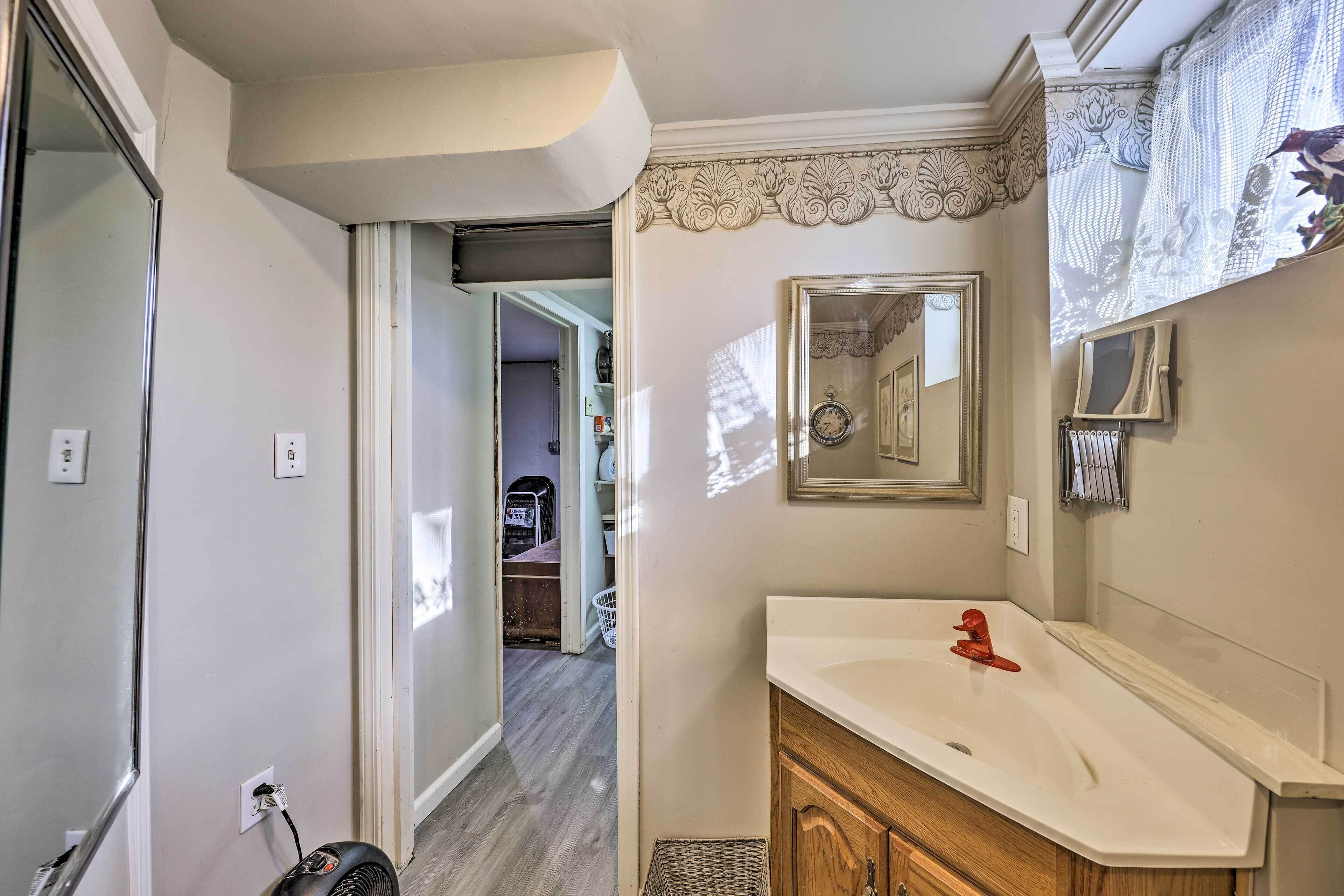 A bathroom with a white sink, wooden cabinets, a mirror, and a ceiling fan.
