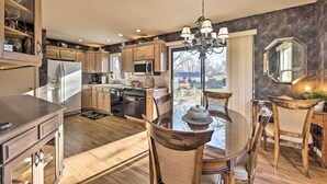 A modern kitchen with wooden cabinets, a dining table with chairs, and a chandelier. - Cozy Kansas City Home w/ Yard - 9 Mi to Dtwn! (Kansas City)