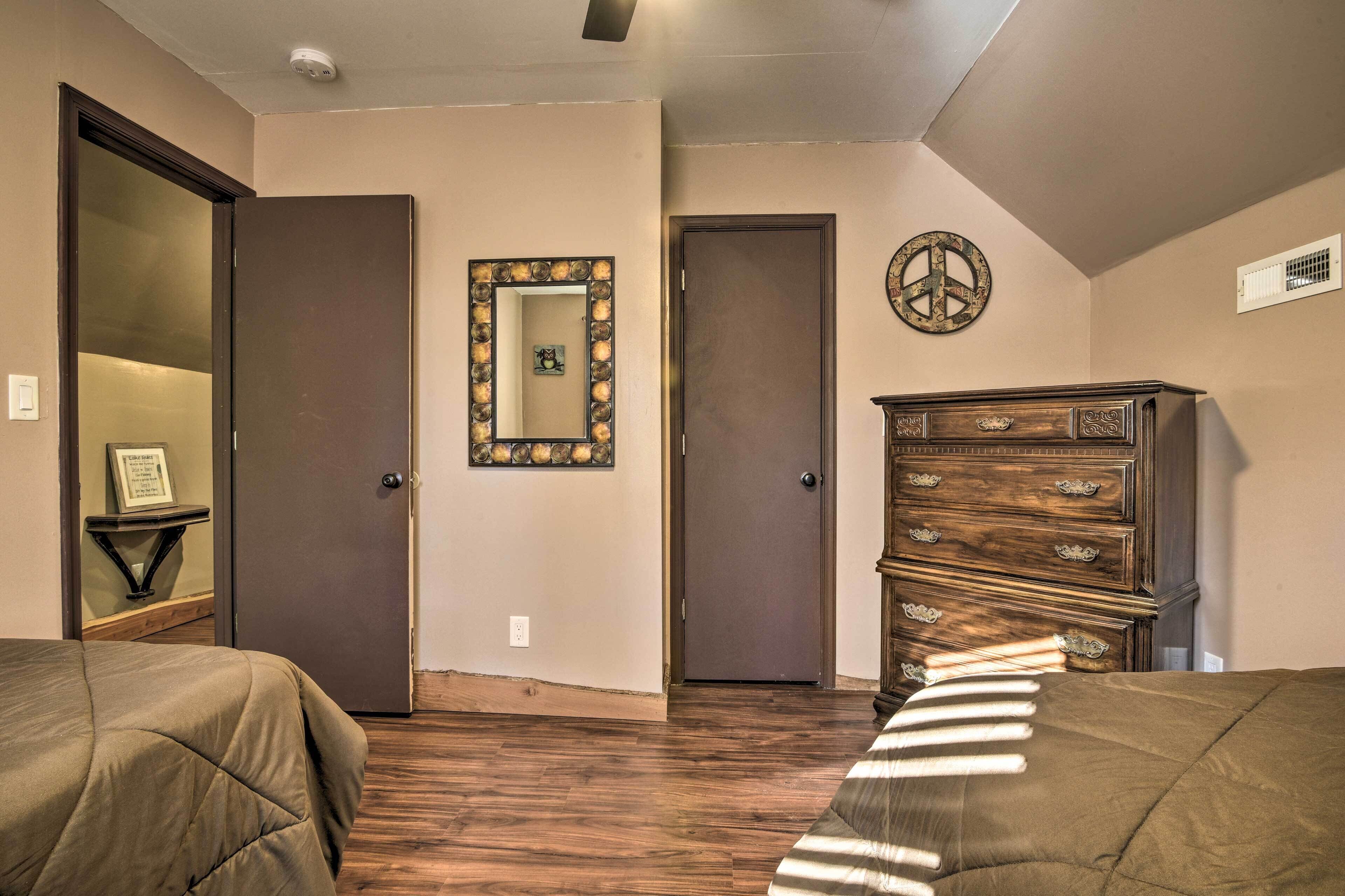A bedroom with two beds, a dresser, a mirror, and a door.