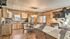A rustic cabin interior with a kitchen, dining area, and a living room with a large sofa. - Dock w/ Boat Slip: Cozy Cabin Near Leesville Lake! (Pittsville)