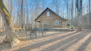 A rustic cabin with a wooden exterior, a porch with chairs, and a dining table. - Dock w/ Boat Slip: Cozy Cabin Near Leesville Lake! (Pittsville)