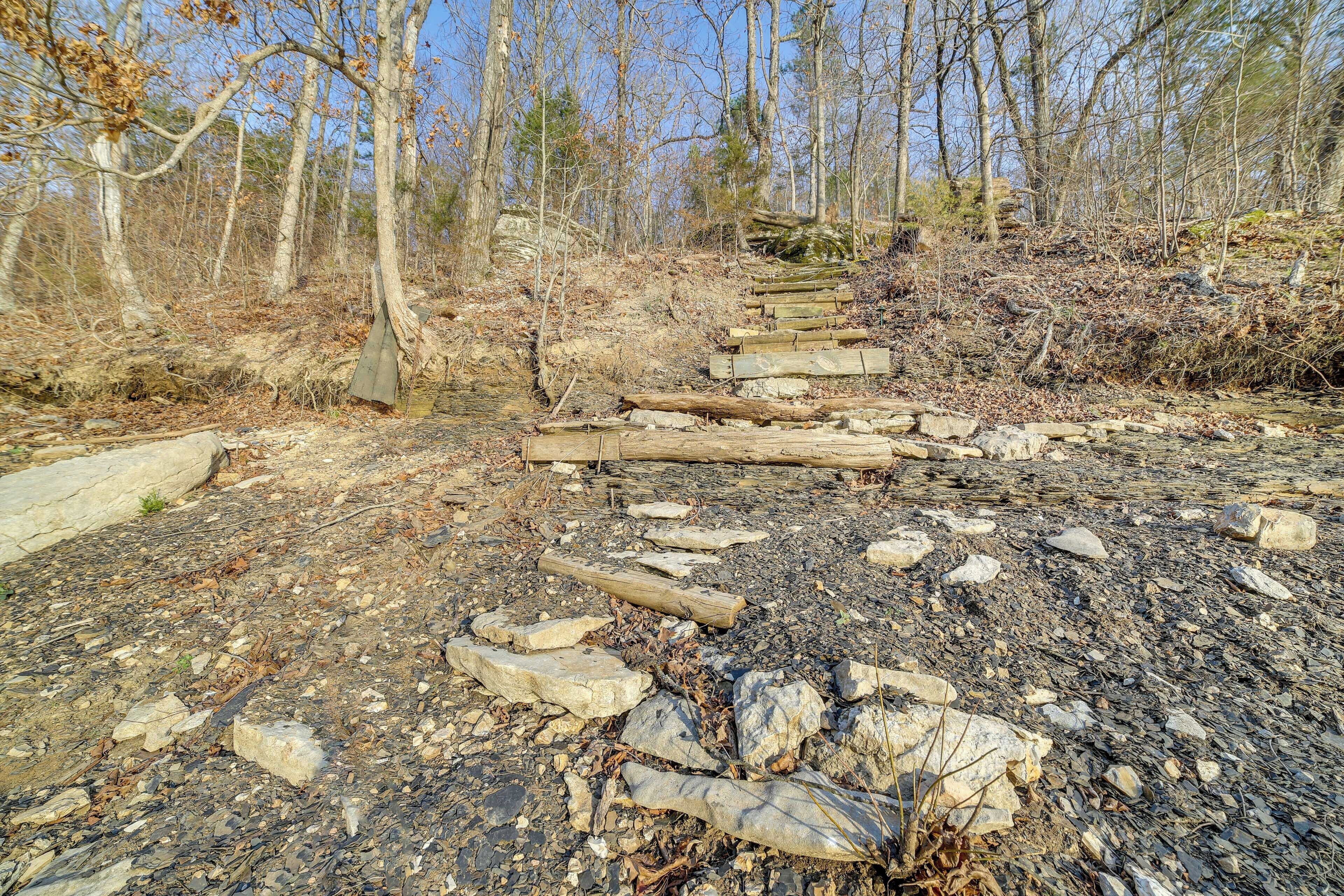 Un sentier rocailleux, agrémenté de marches en bois, qui monte une colline, entouré d’arbres et de feuilles mortes.