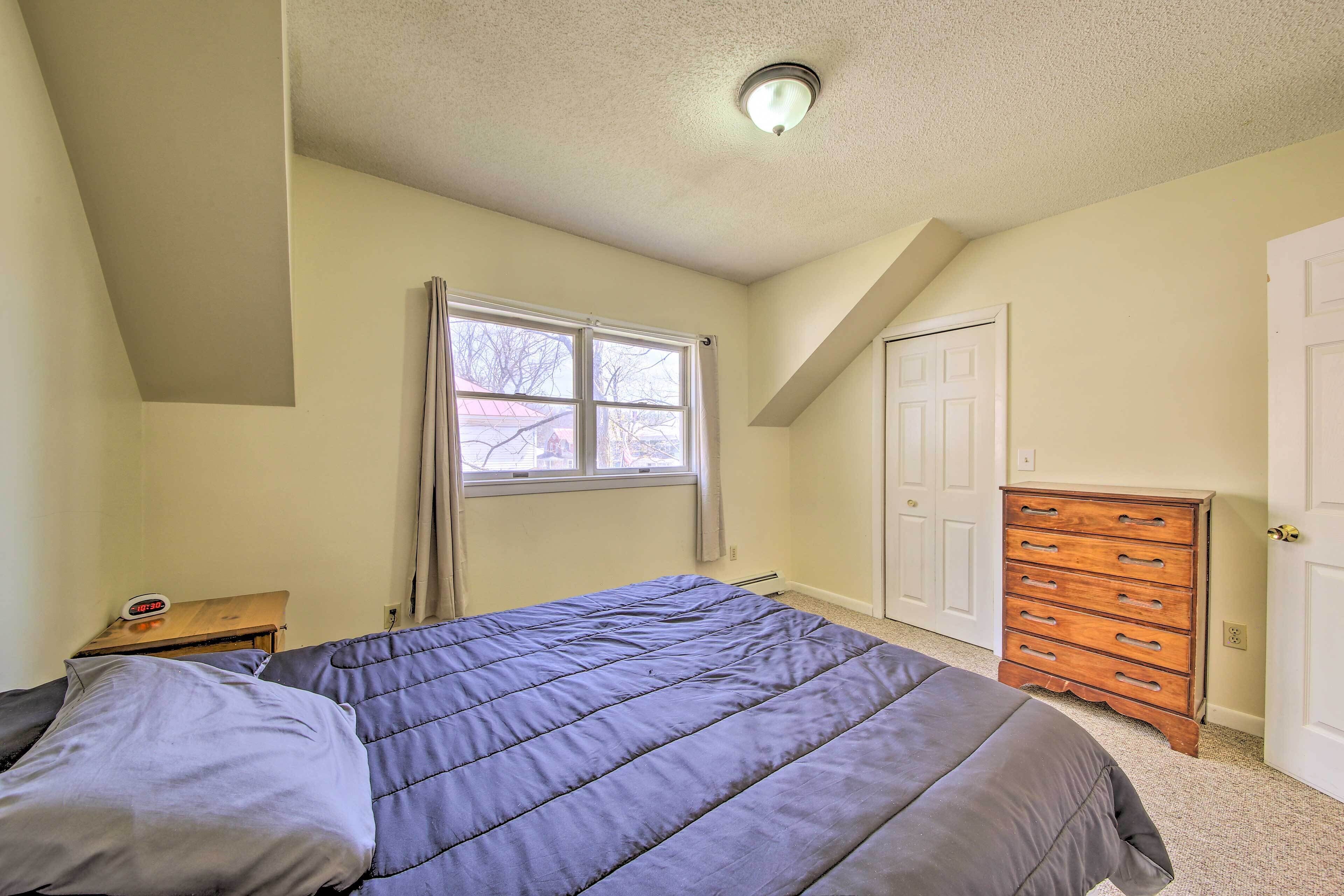 A bedroom with a bed, a dresser, a window, and a door.