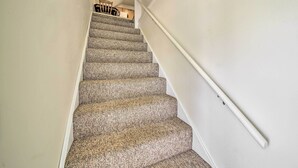 A carpeted staircase with a handrail, leading to a room with a chair and a table. - Cozy Bingham Apt, 1 Mi to Rafting & ATV Trail (Bingham)