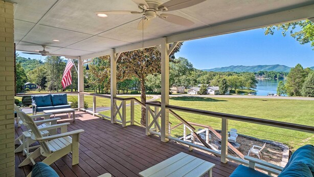 A covered deck with white Adirondack chairs, a small table, and a ceiling fan. - Hayesville Lake Getaway w/ Balcony & Mtn Views! (Hayesville)