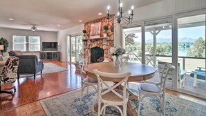A spacious living room with a fireplace, a dining table, and a view of the outdoors. - Hayesville Lake Getaway w/ Balcony & Mtn Views! (Hayesville)