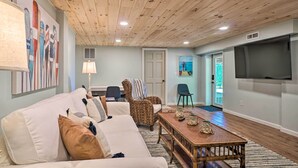 A living room with a wooden ceiling, a sofa, a chair, a coffee table, and a TV mounted on the wall. - Hayesville Lake Getaway w/ Balcony & Mtn Views! (Hayesville)