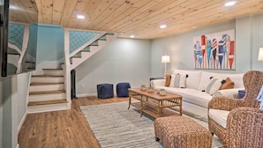 A modern living room with a wooden staircase, a white sofa, a woven armchair, and a coffee table. - Hayesville Lake Getaway w/ Balcony & Mtn Views! (Hayesville)