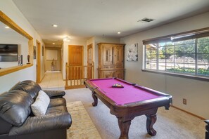 A room with a pool table, a leather sofa, a wooden cabinet, and a window with a view. - Spacious Lancaster Family Ranch - BBQ & Patio (Lancaster)