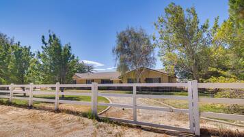 A fenced property with a house, trees, and a clear sky.