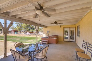 A covered patio with a table and chairs, a ceiling fan, and a hot tub. - Spacious Lancaster Family Ranch - BBQ & Patio (Lancaster)