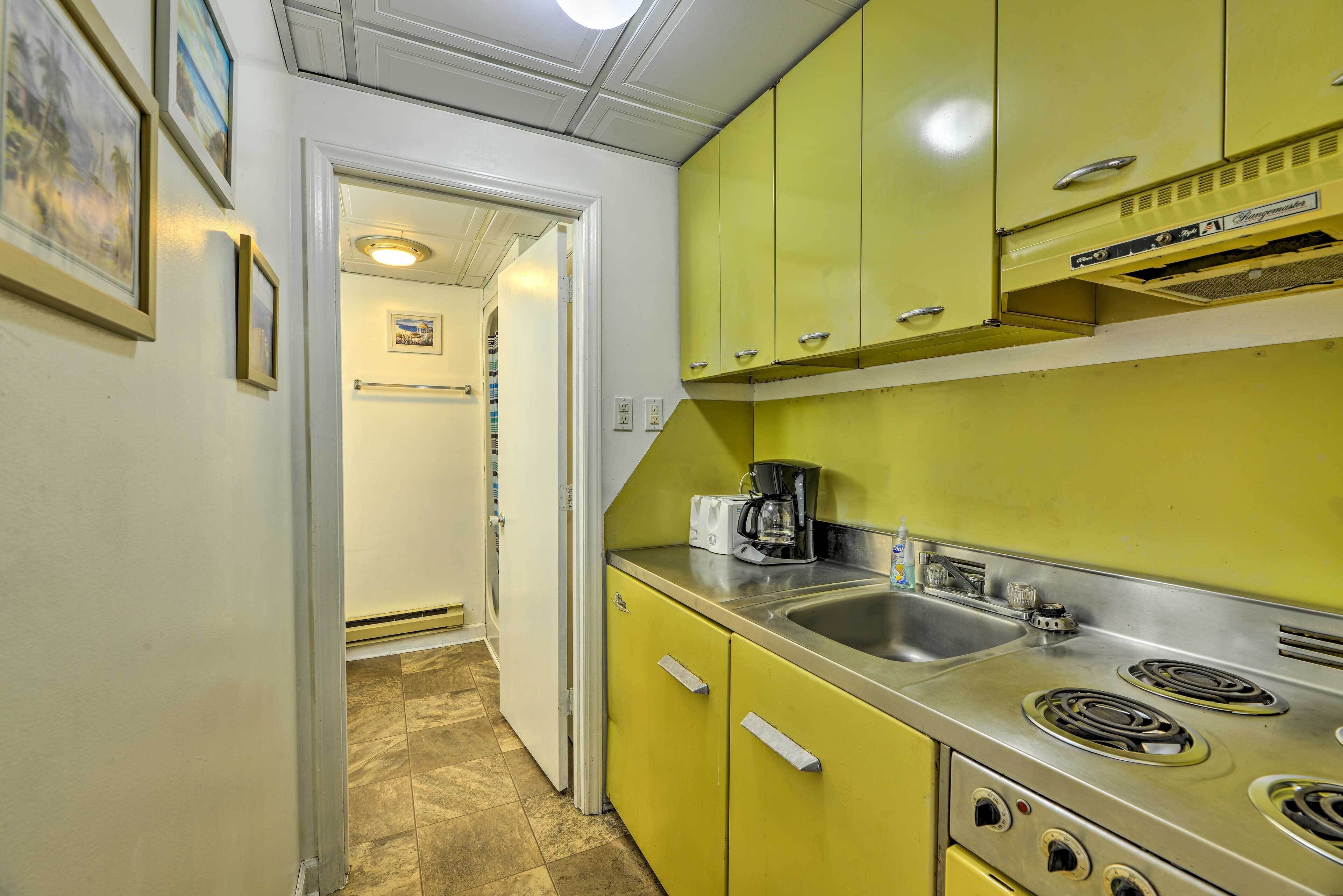 A kitchen with yellow cabinets, a stainless steel sink, and a stove.