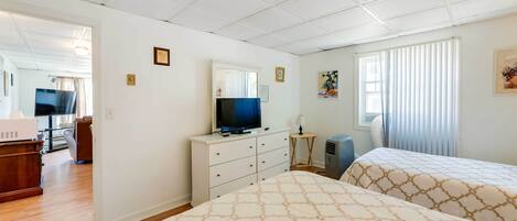 A hotel room with two beds, a TV on a dresser, a desk, and a chair.