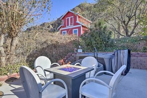 A patio with a square table and white chairs, a fire pit, and a red house in the background. - On-site Trails! Hot Tub Hideaway in Zion Area (Hurricane)