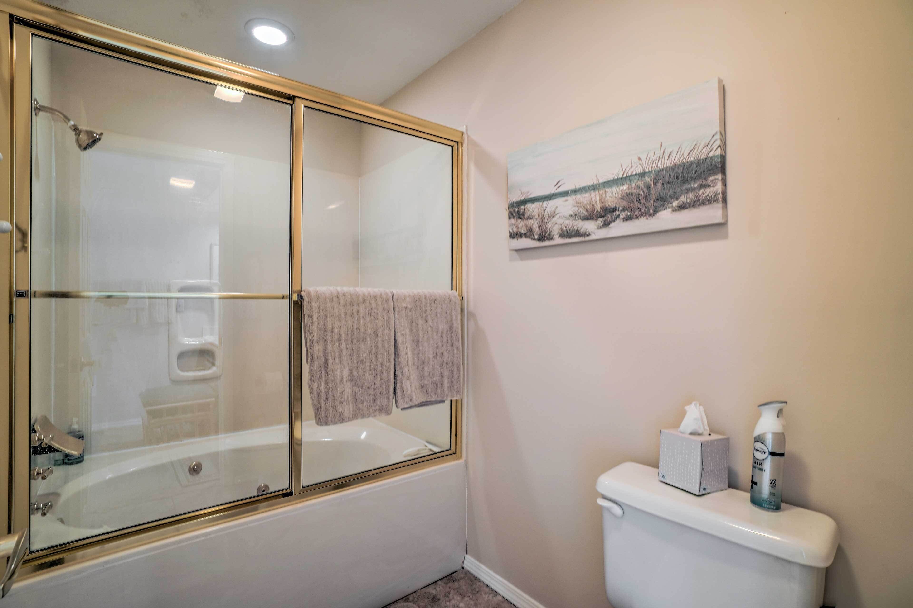 Un bagno con doccia vetrata, un water e un quadro appeso al muro.