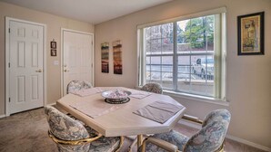 A dining room with a large oval table, four chairs, and a window with a view of the street. - Branson Condo w/ Sunroom Near Downtown! (Branson)
