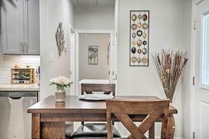 Un comedor con una mesa y sillas de madera, un jarrón con flores y una obra de arte en la pared.