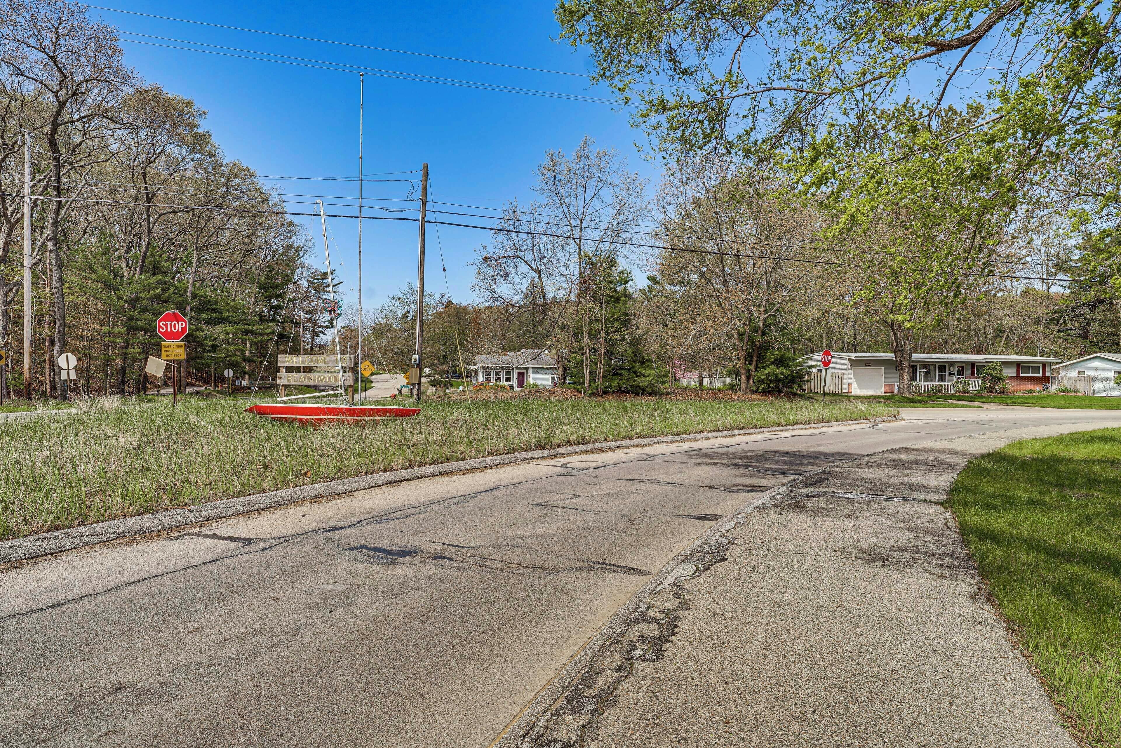 A quiet suburban street with a stop sign, a red boat on the grass, and houses in the background.