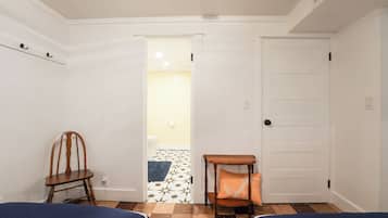 Une pièce comprenant une chaise en bois, une petite table avec un coussin et une porte donnant sur une salle de bain.