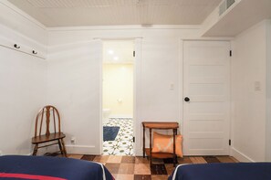 A room with a wooden chair, a small table with a cushion, and a door leading to a bathroom. - Walk to Beach: Lake Michigan Getaway! (Muskegon)