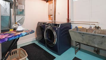 Un cuarto de lavandería con lavadora, un lavamanos y un tendedero.