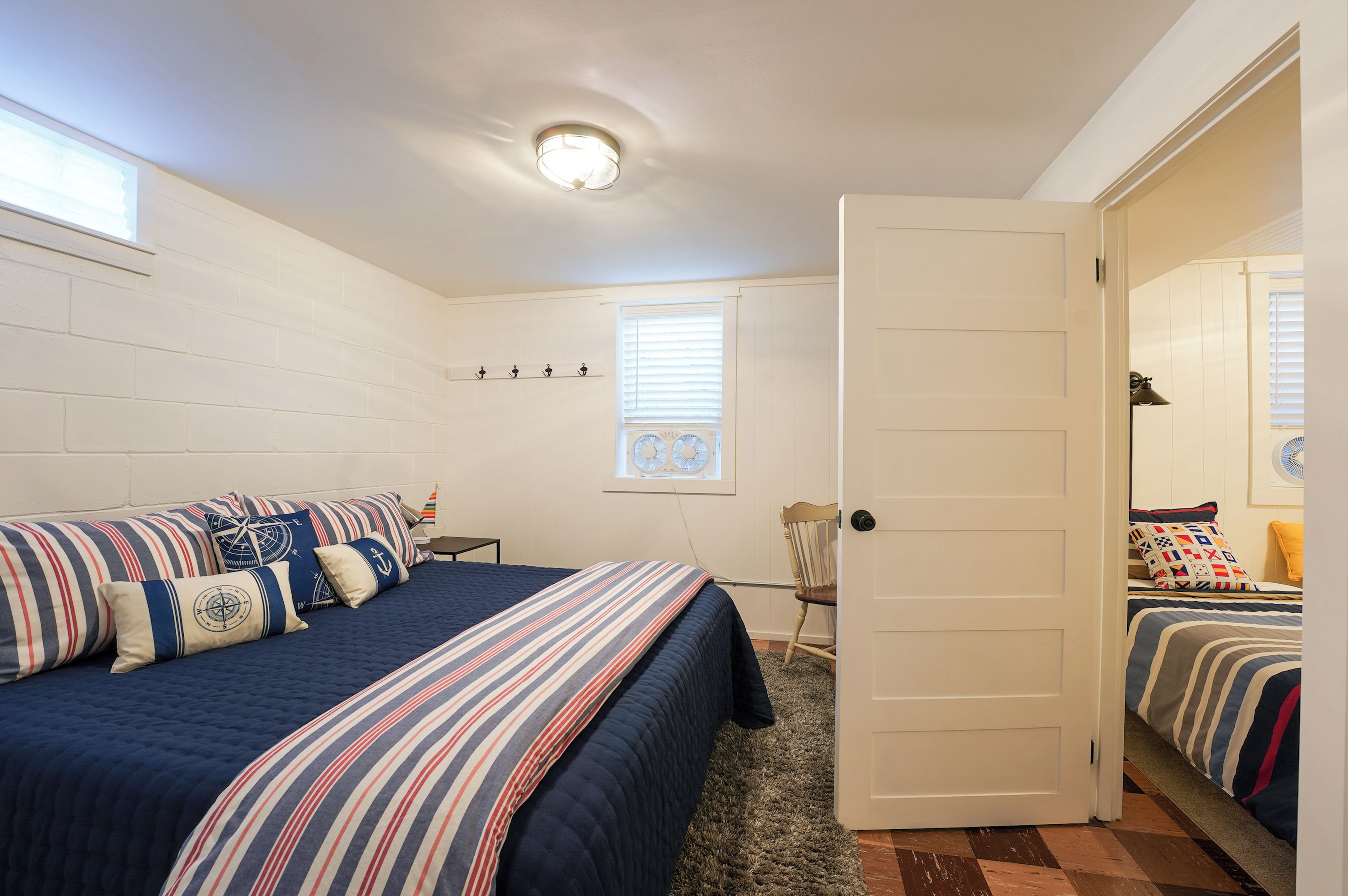A bedroom with a bed, a chair, a door, and a window with blinds.
