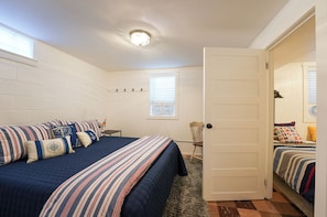A bedroom with a bed, a chair, a door, and a window with blinds.