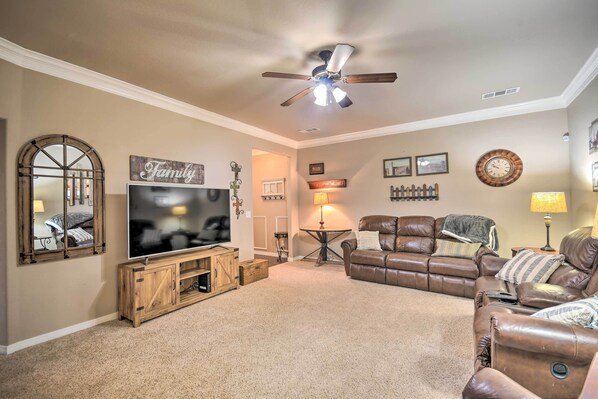 A living room with a large flat-screen TV, a ceiling fan, a brown leather sofa, a wooden entertainment unit, and a 'Family' sign on the wall. - Inviting Amarillo Gem Near Palo Duro Canyon! (Amarillo)