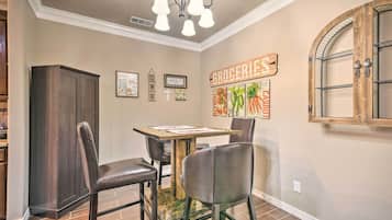 A dining area with a wooden table, four chairs, and a chandelier.