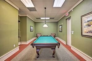 A pool table in a room with green walls and a red carpet.