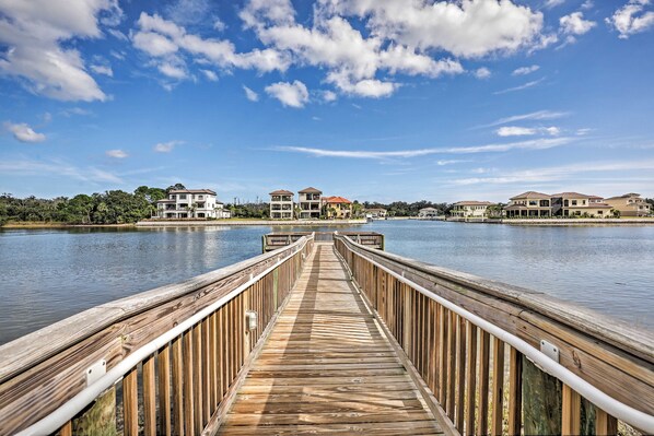 A wooden pier leading to a waterfront with multiple buildings.