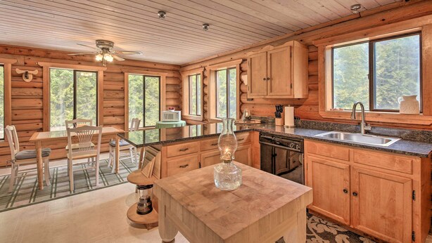 A wooden cabin kitchen with a dining area, large windows, and a central island. - Riverfront Troy Cabin Ready With Bikes & Rafts! (Troy)