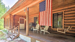 A wooden cabin with a porch, an American flag, and outdoor seating. - Riverfront Troy Cabin Ready With Bikes & Rafts! (Troy)