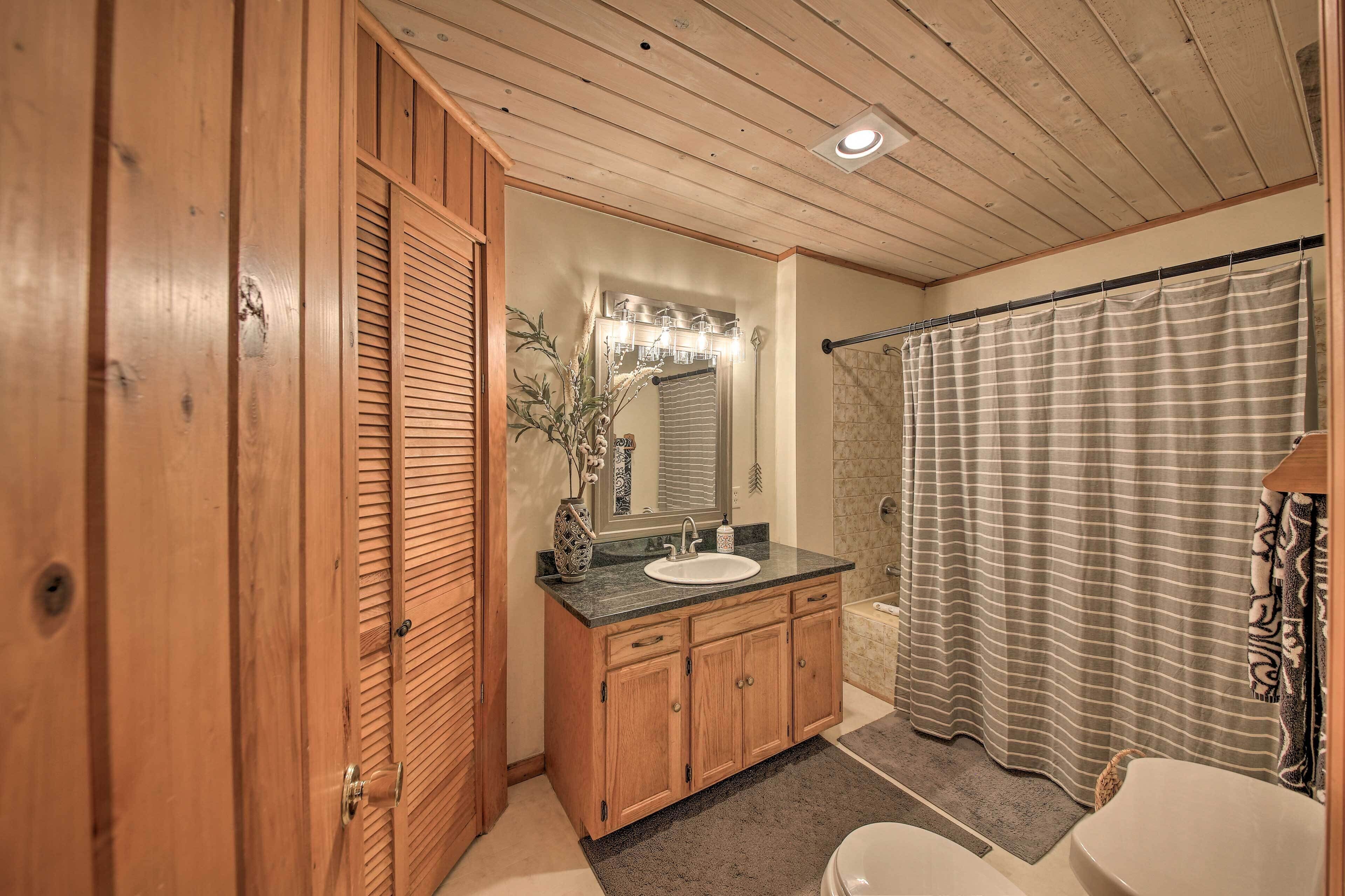 A bathroom with wooden cabinets, a sink, a mirror, and a shower curtain.