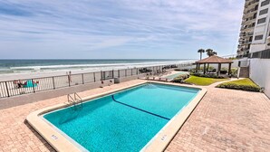 A rectangular swimming pool with a tiled deck, a gazebo, and a view of the ocean. - Oceanfront Retreat w/ Beach & Resort Access! (Daytona Beach Shores)