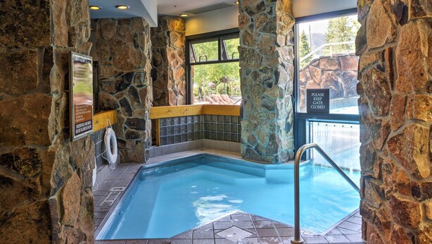 A stone-walled indoor pool with a clear view of the outdoors, a lifeguard chair, and a sign indicating the pool is closed. - Big Sky Condo w/ Mountain Views, Hike, Ski & Fish! (Big Sky)
