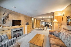 Een moderne woonkamer met een open haard, bank en televisie.