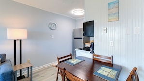 A compact living space with a dining area, kitchenette, and a clock on the wall. - Beachfront Family Condo w/ Stunning Views! (Sneads Ferry)